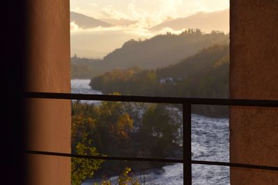 Scenic view of mountains seen through window during sunset