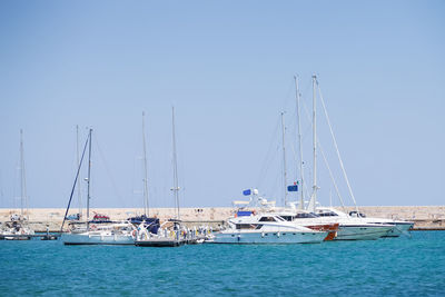 Sailboats moored in sea against clear sky