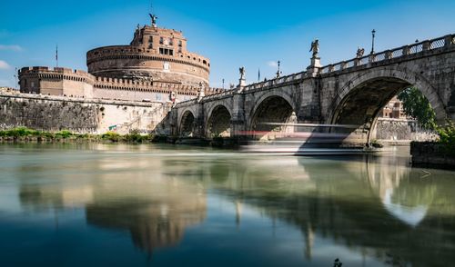 Arch bridge over river against buildings in city