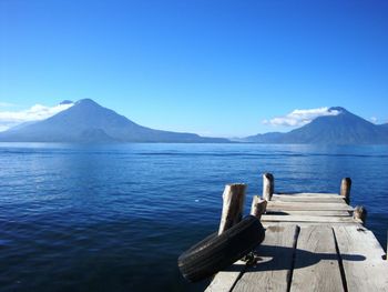 Scenic view of lake and mountains against clear blue sky