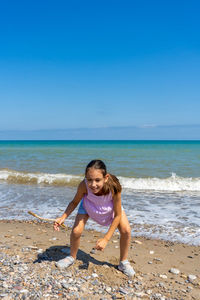 Portrait of girls bending on beach against sky