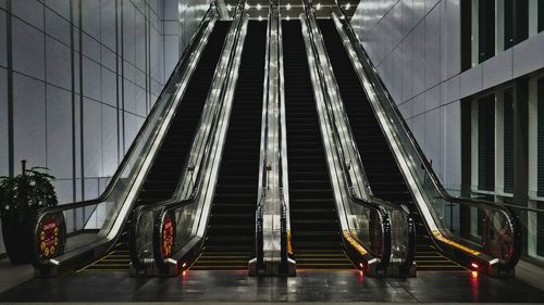 Low angle view of illuminated stairs escalator against buildings in city