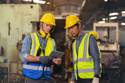 Engineers in an industry plant setting up machines vs a background of a machine factory.