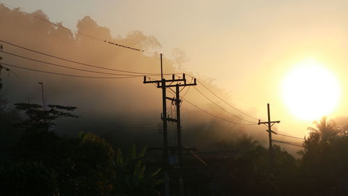 Silhouette electricity pylon against sky during sunset