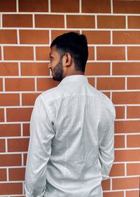 Rear view of man standing against brick wall