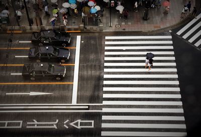 High angle view of people holding umbrella while walking on city street