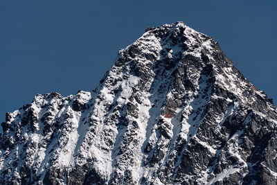 Low angle view of snowcapped mountain against clear blue sky