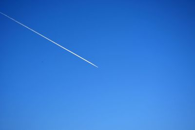 Low angle view of vapor trail in clear blue sky