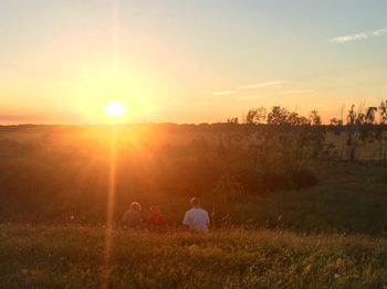 Scenic view of grassy field against sky at sunset