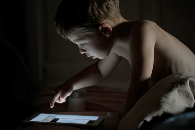 Close-up of shirtless boy using digital tablet at home