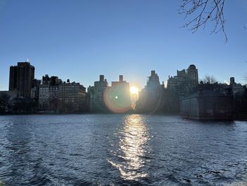 River and buildings against clear sky during sunset