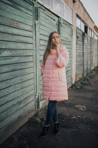 Full length of woman standing against pink umbrella