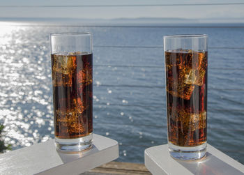 Close-up of beer on table against sea