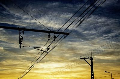 Low angle view of electricity pylon against cloudy sky