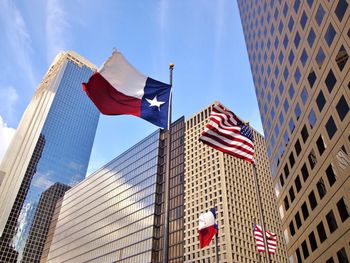 Low angle view of flags against modern buildings