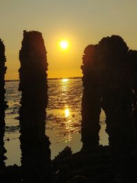 Silhouette trees by sea against sky during sunset