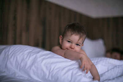 Close-up of cute baby boy lying on bed at home