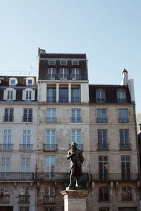 Low angle view of statue against building in city against sky
