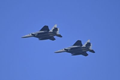 A pair of f-15 eagles flying  against clear blue sky