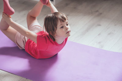 Child performs the exercise gymnastics at home on a mat. home workouts. health and sports. 