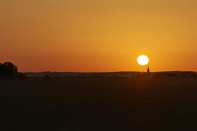 Scenic view of silhouette field against orange sky