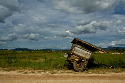 Cart on agricultural field against sky