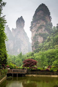 Built structure on rocks by trees against sky