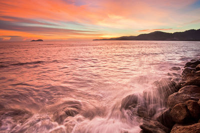Scenic view of sea against dramatic sky during sunset