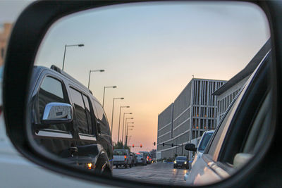 Vehicles on road against sky during sunset