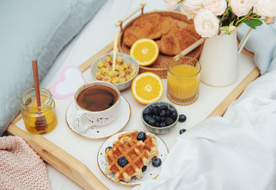 Romantic breakfast with coffee, waffles, orange juice and rose flowers.