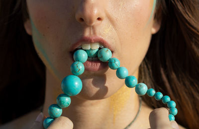 Close-up of woman carrying beaded necklace in mouth