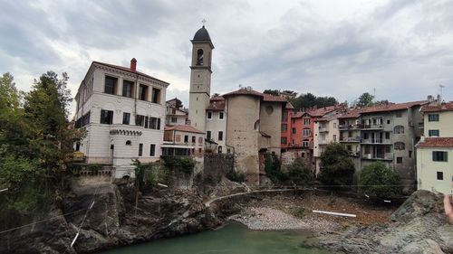 Buildings by river against sky