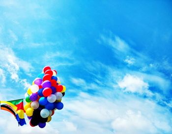 Low angle view of balloons flying against blue sky