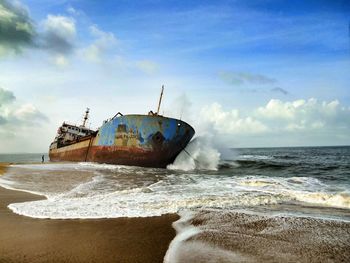 Abandoned ship on beach against sky