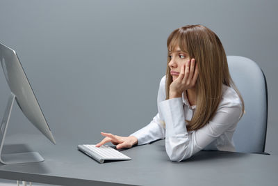 Young woman using laptop while sitting on bed at home