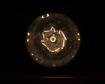 Close-up of illuminated electric lamp in darkroom