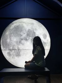 Side view of woman sitting against sky