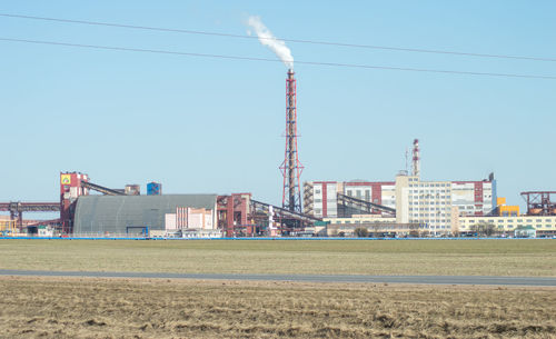 Crane on field by buildings against sky