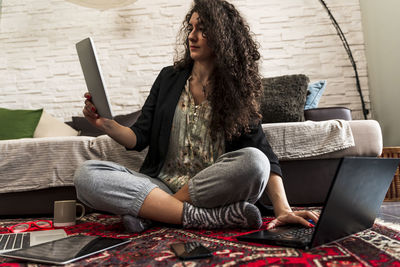 Young woman is working at home on the computer on floor during the restrictions due to the covid-19