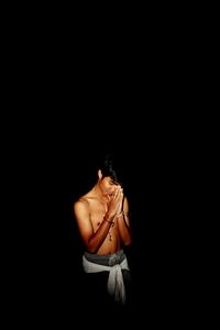 Shirtless teenage boy praying at night