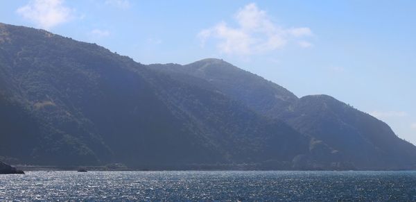 Scenic view of sea and mountains against sky