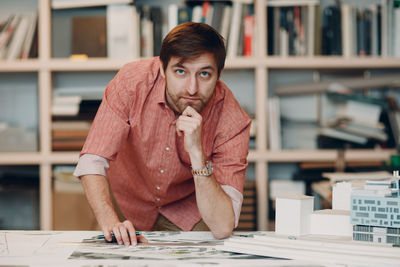 Portrait of young man with book on table