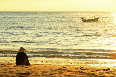 Rear view of man sitting on beach