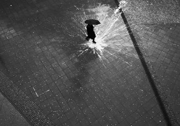 High angle view of silhouette man walking on wet street during rainy season