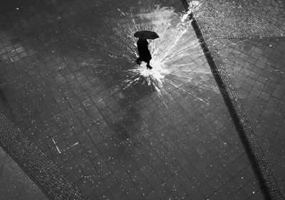 High angle view of silhouette man walking on wet street during rainy season