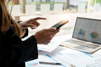 Midsection of woman using laptop on table