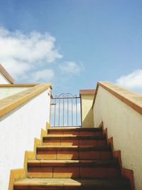 Low angle view of staircase and gate against sky