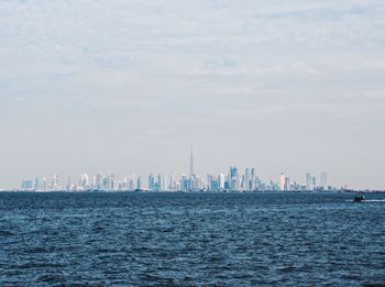 Sea by modern buildings against sky