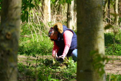 Man climbing on tree trunk in forest