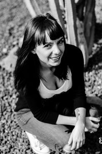 High angle portrait of happy woman crouching on sunny day